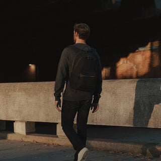 Back view of a man wearing a Commuter in Black while walking down a street.