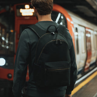 The back of a man walking towards a train with a Commuter in Black.